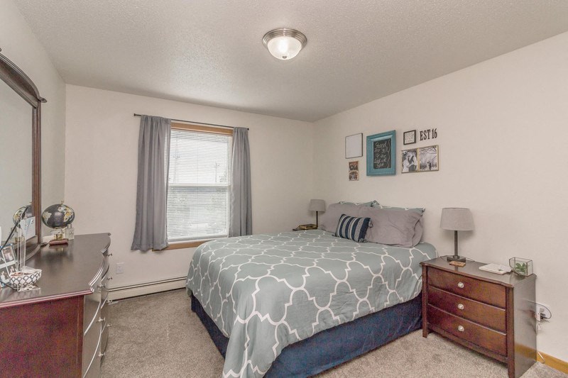 a bedroom with a bed and a dresser and a window