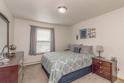 a bedroom with a bed and a dresser and a window
