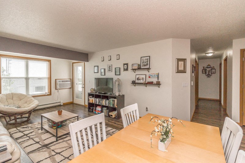a dining room and living room with a wooden table and chairs