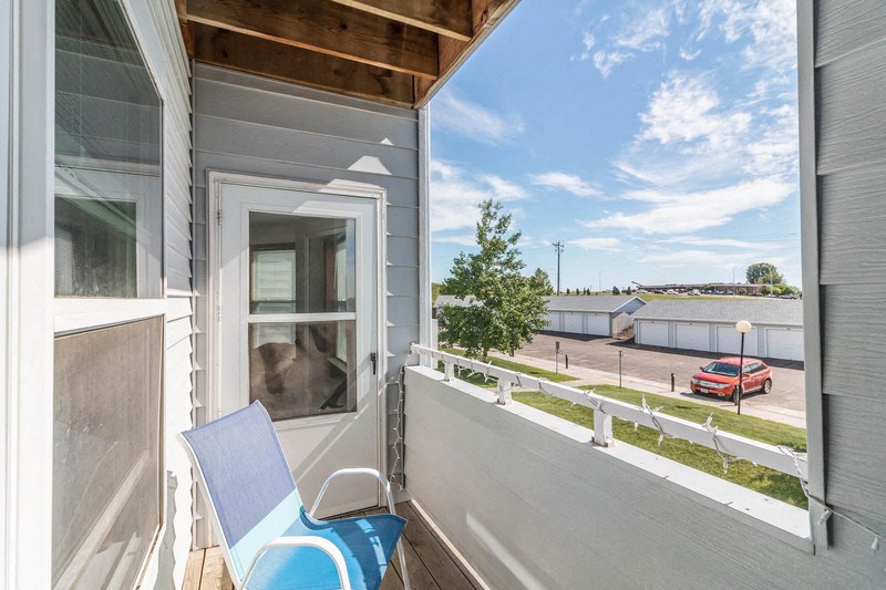 a small porch with a blue chair and a window
