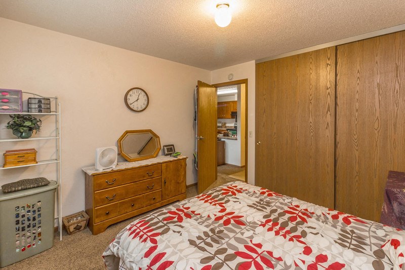a bedroom with a bed and a dresser and a clock on the wall