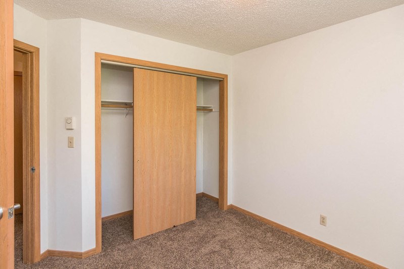 an empty bedroom with a door to a closet