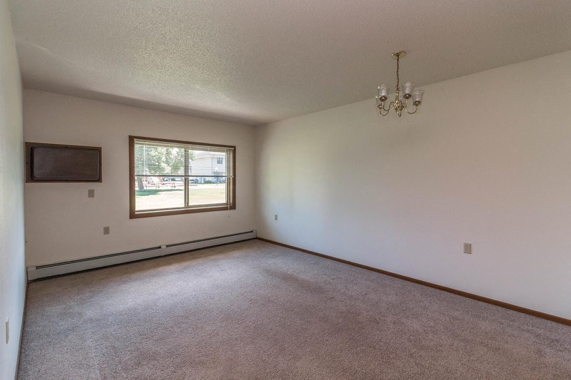 an empty living room with a window and a chandelier