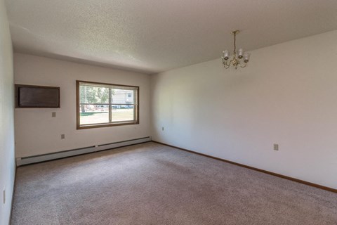 an empty living room with a window and a chandelier