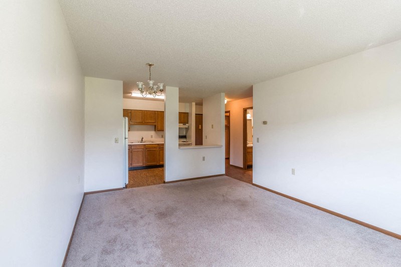 an empty living room and kitchen with white walls and carpet