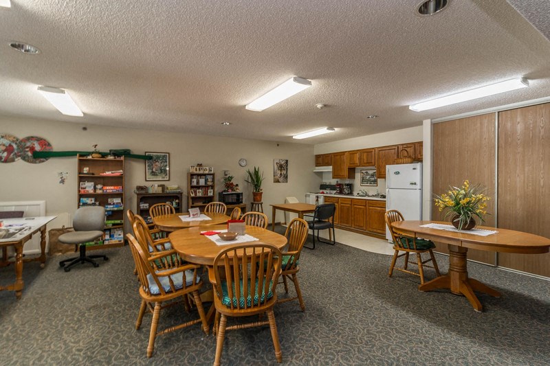 a dining room with tables and chairs and a kitchen