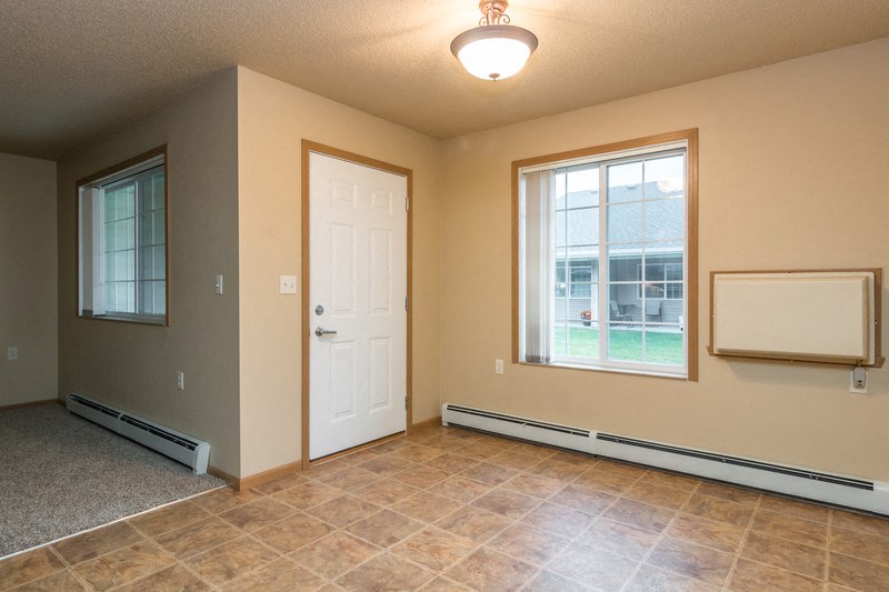 a empty living room with a white door and a window