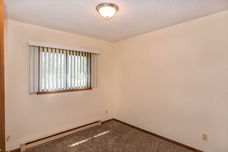 the living room of an empty house with a window and a carpet