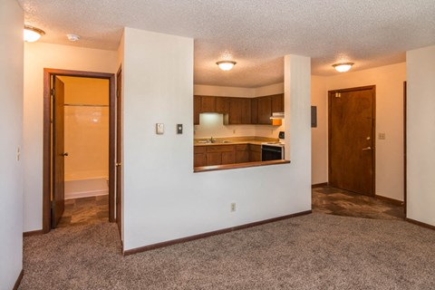 the view of a kitchen from a living room with the door open