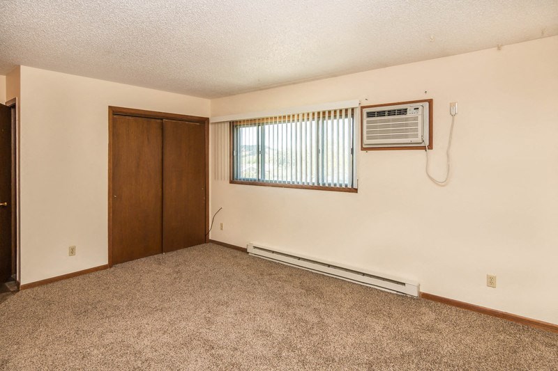 an empty living room with an air conditioner and a window