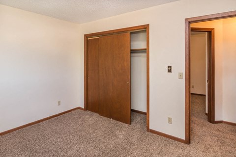 a bedroom with a door to a closet and a carpeted floor