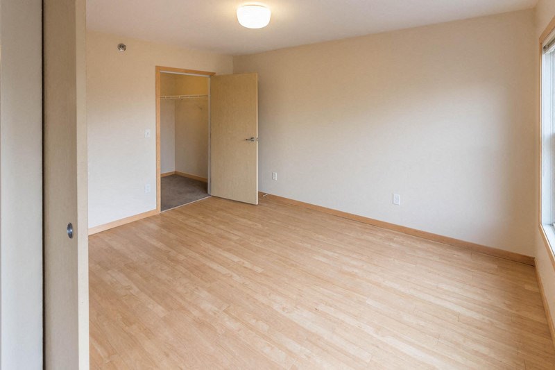 an empty living room with wood flooring and a closet