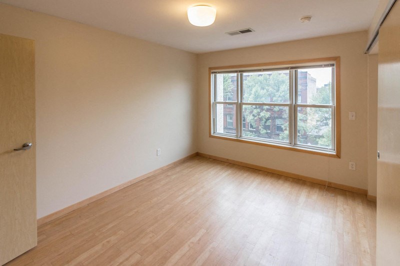 an empty living room with wood floors and a large window