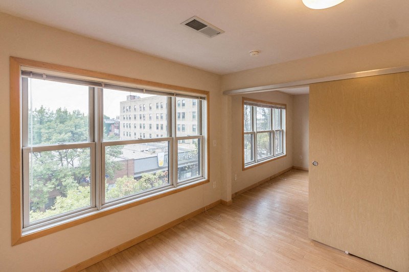 an empty living room with large windows and wood flooring