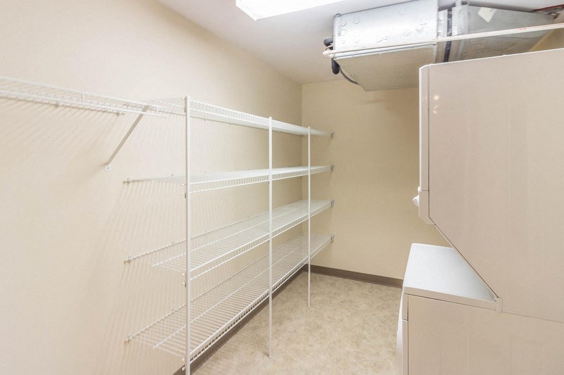 a white closet with white shelves and a white refrigerator