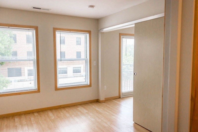 an empty living room with a hard wood floor and three windows