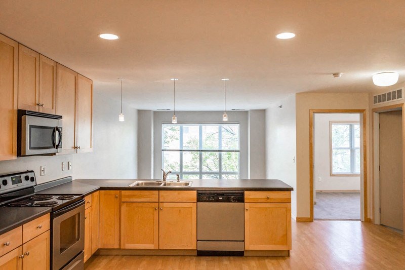 an empty kitchen with wooden cabinets and stainless steel appliances