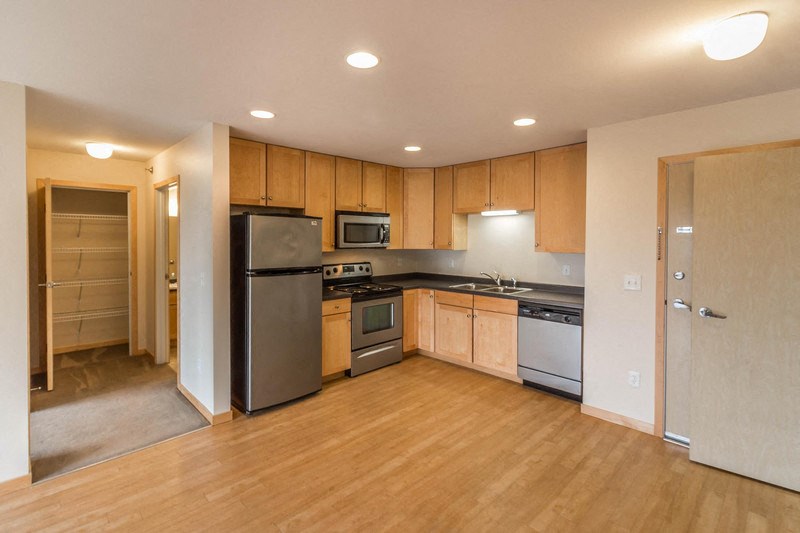 an empty kitchen with wooden cabinets and stainless steel appliances