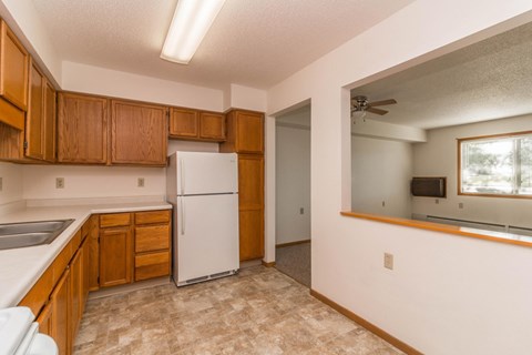 A kitchen with a white refrigerator and wooden cabinets.
