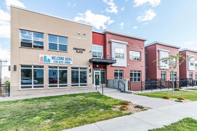 the front of a building with a sidewalk and grass