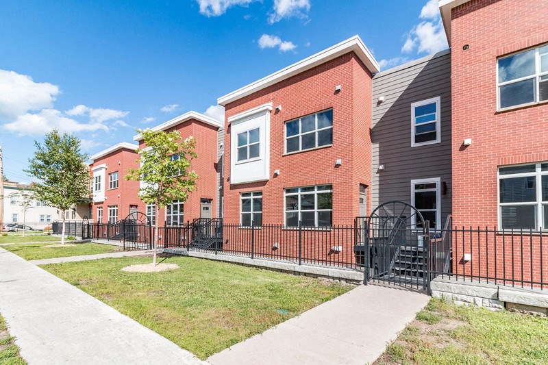 the outlook of a brick building with a sidewalk and a fence