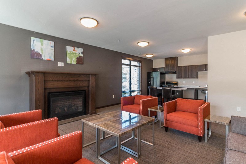 a living room with a fireplace and orange chairs