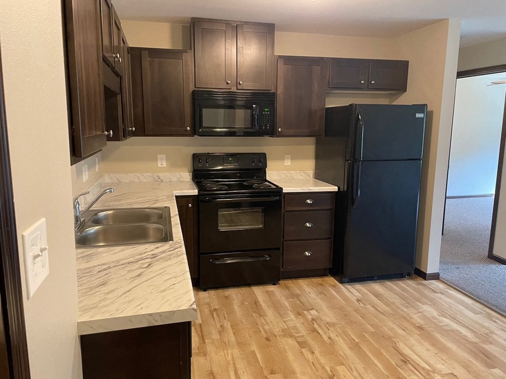 a kitchen with black appliances and wooden floors