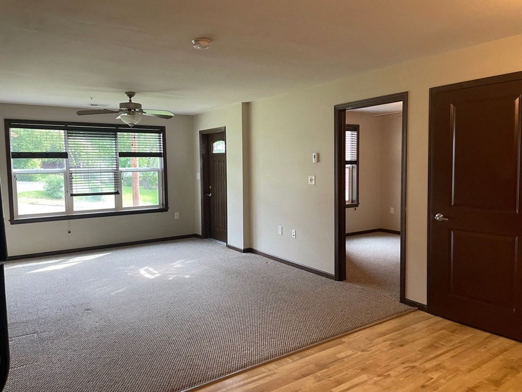 an empty living room with a ceiling fan and a window
