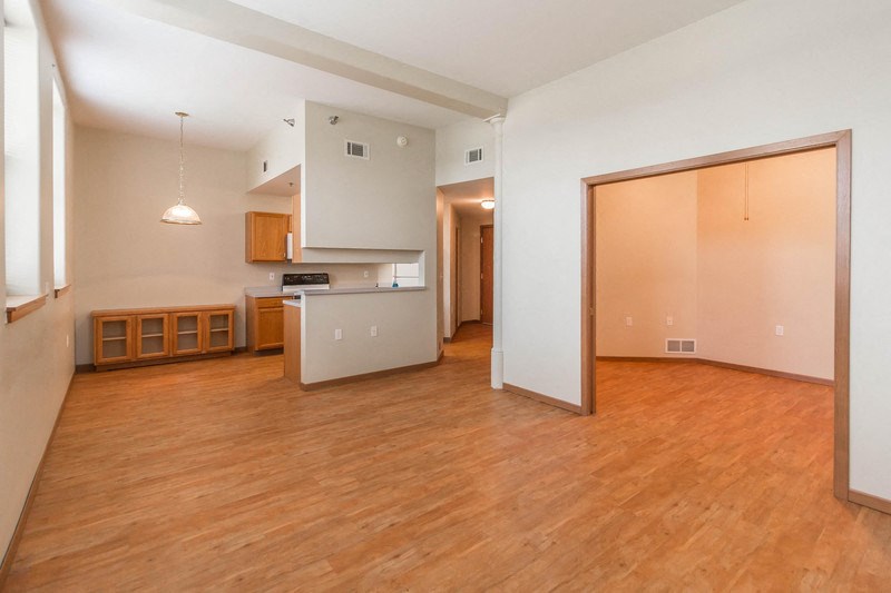 an empty living room and kitchen with a wood floor