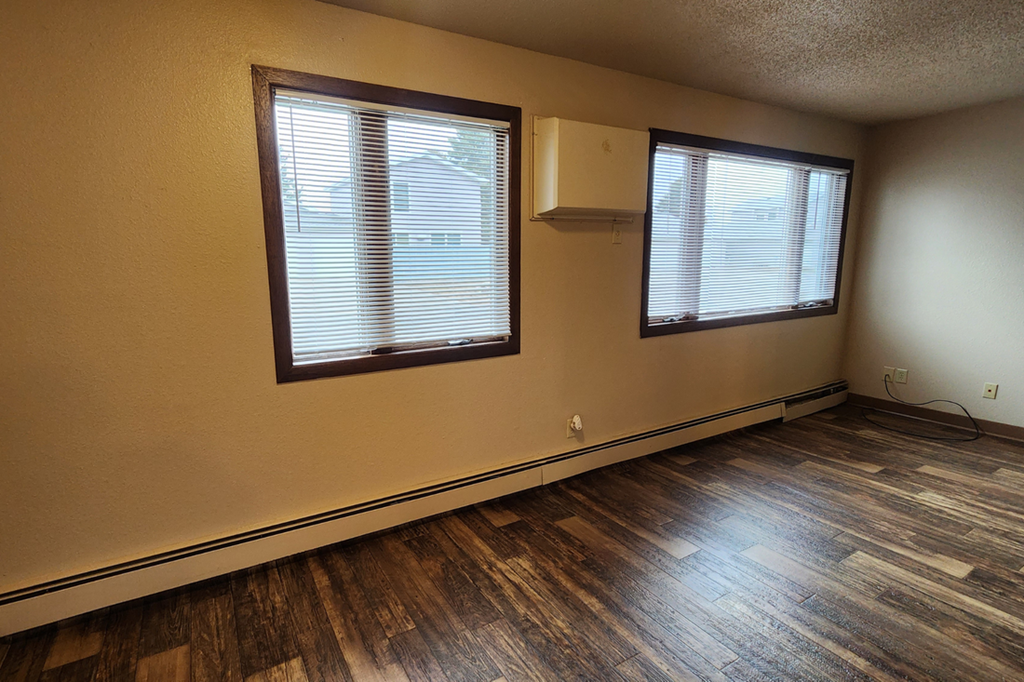 the living room of an empty house with wood floors and two windows