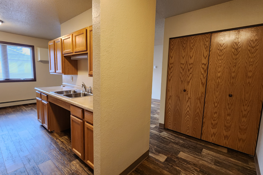 a kitchen with wooden cabinets and a sink and a wooden floor