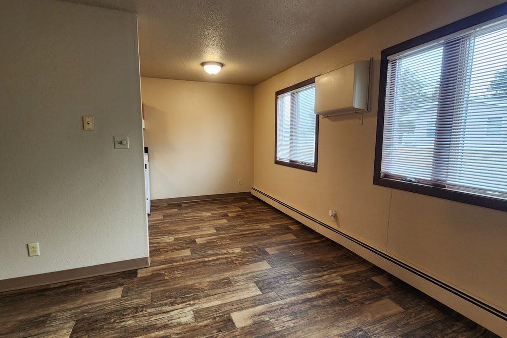 an empty living room with a large window and wood floors