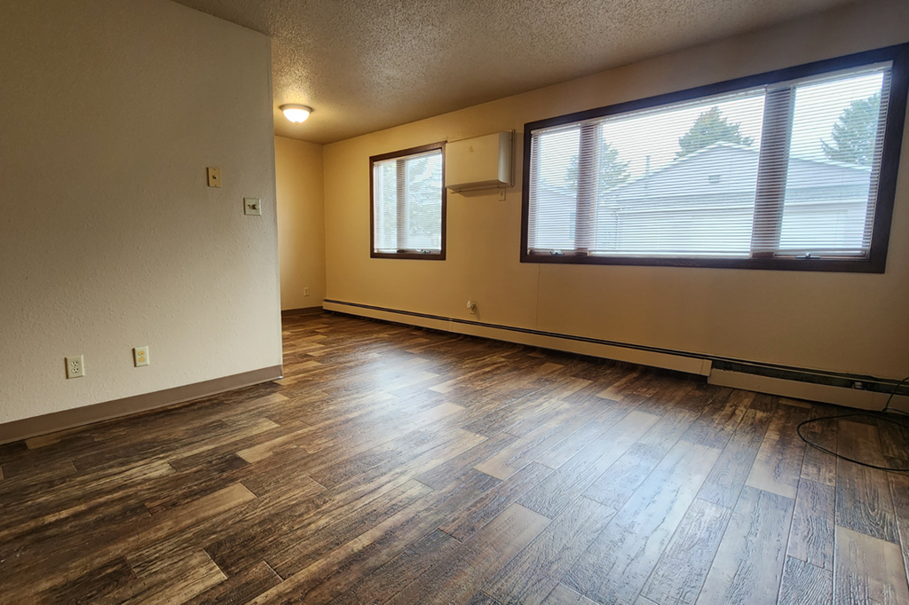 the living room of an empty house with wood floors and a window