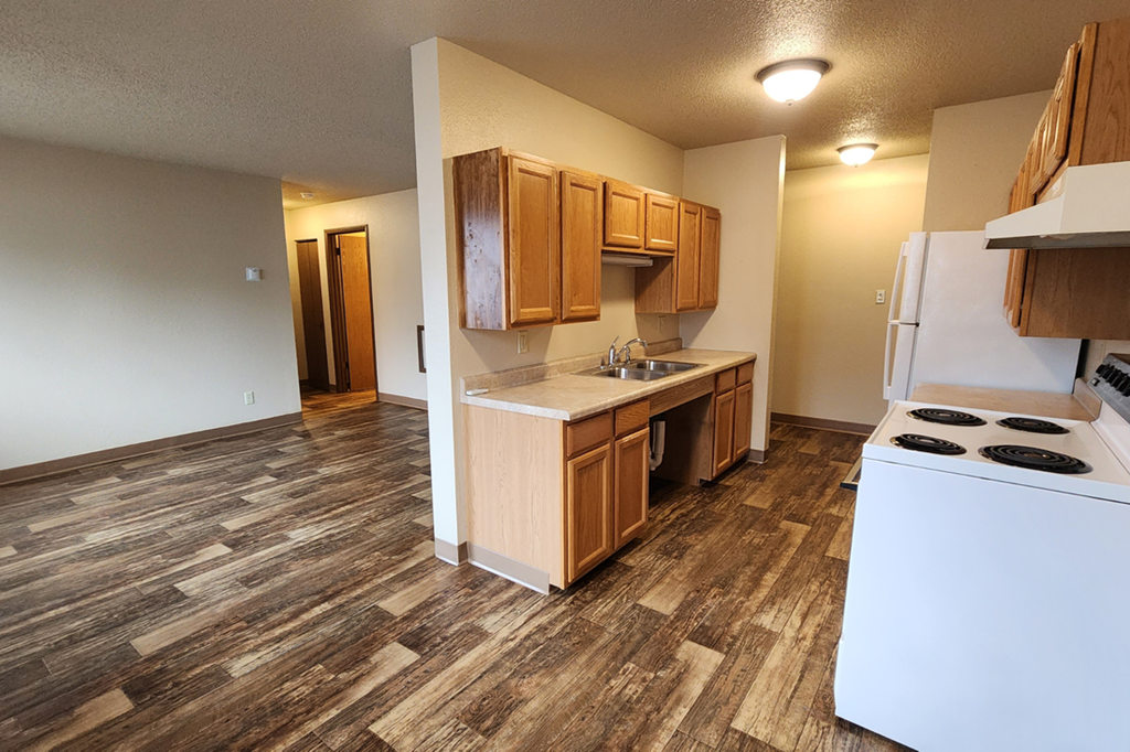 an empty kitchen with wood flooring in an apartment