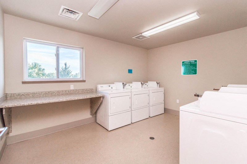 a laundry room with washers and dryers and a counter and a window