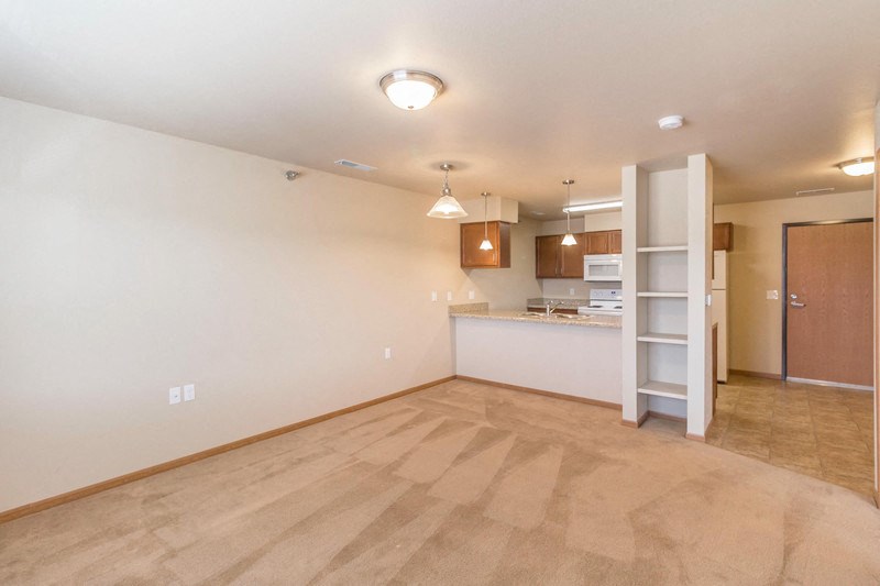 the living room and kitchen of an empty house with a ladder in the corner