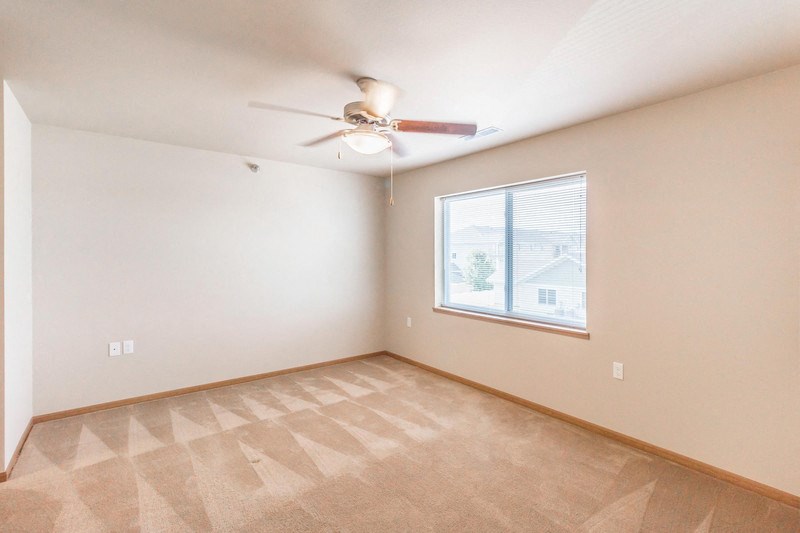 an empty living room with a ceiling fan and a window
