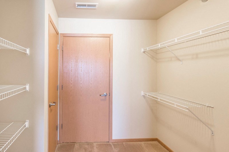 a walk in closet with a sliding door and a white closet