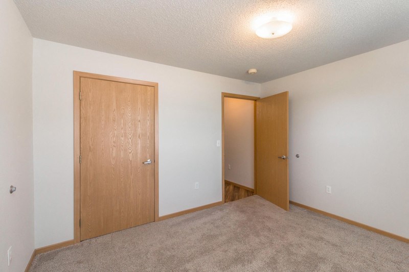 the living room of an empty apartment with a door to the hallway