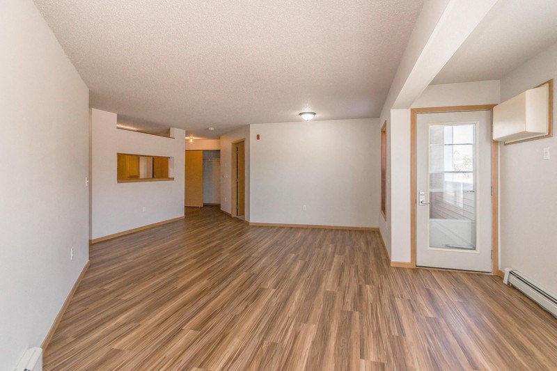 an empty living room with wood flooring and a glass door