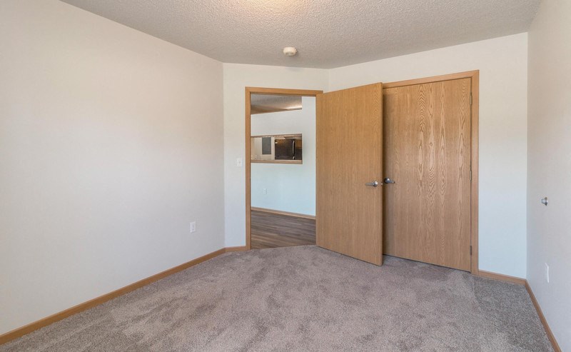 the living room of an apartment with a door to the hallway and a bedroom door