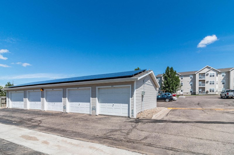 a garage with white doors in a parking lot with apartment buildings