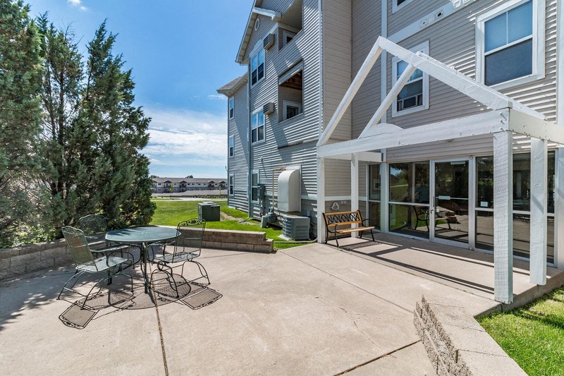 a patio with a table and chairs in front of a house