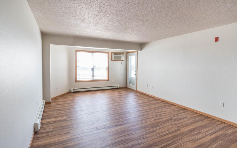 the living room and dining room of an empty house with wood floors and a window