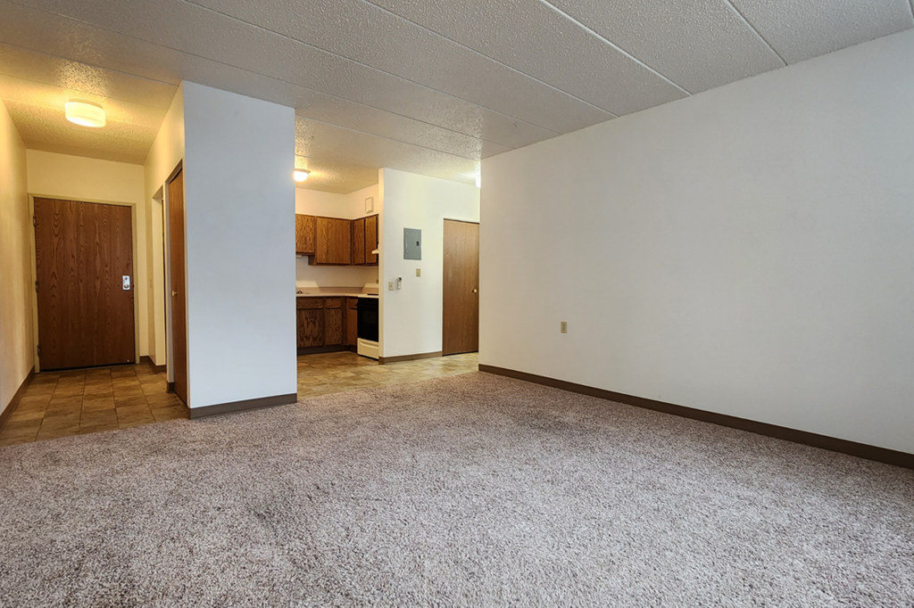 the living room and kitchen of an empty apartment with white walls