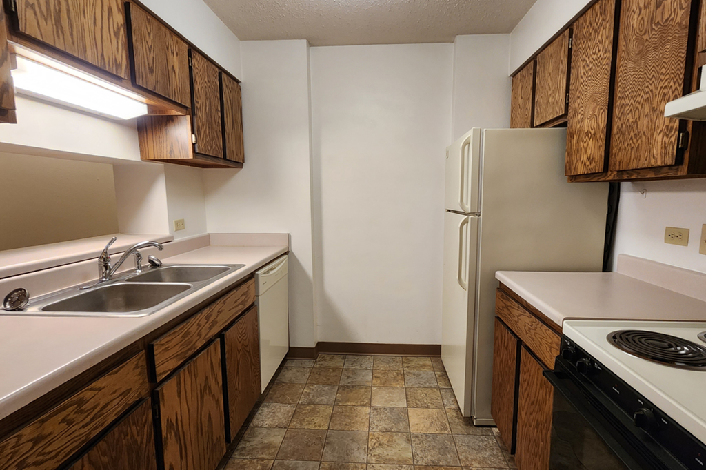 an empty kitchen with a sink and a refrigerator