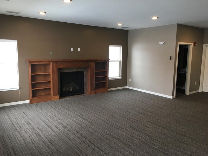 an empty living room with a fireplace and wooden shelves