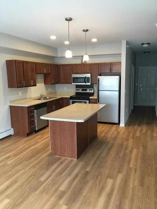 an empty kitchen with wooden floors and stainless steel appliances