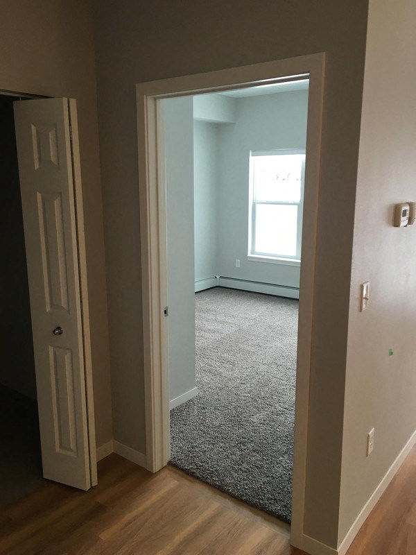 a room with a door and a carpeted floor and a window