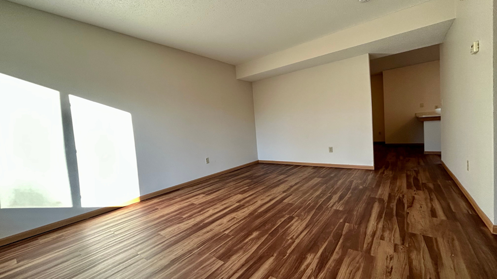 an empty living room with wooden floors and white walls